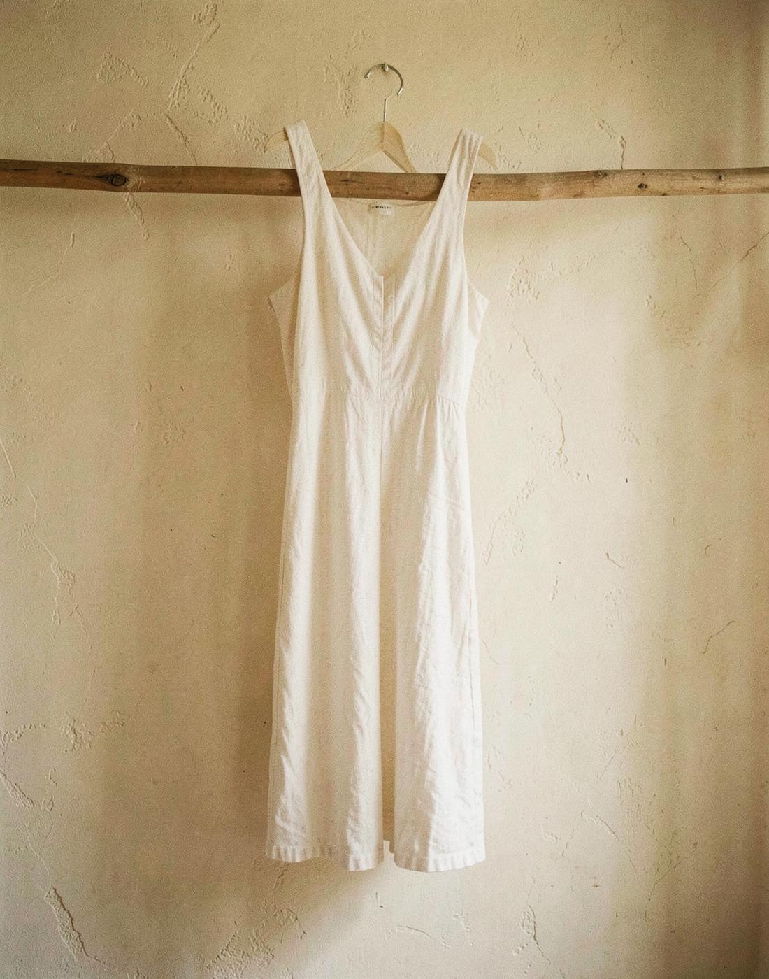 The 03 Dress in washed chalk linen, hanging on a wooden rail